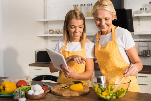 Happy Mature Woman Adult Daughter Using Digital Tablet While Cooking — Stock Photo, Image