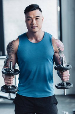 Genç Asyalı sporcu spor salonu concentrarted dumbbells ile egzersiz konsantre 