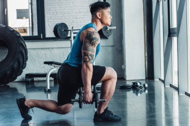 genç sporcu spor salonunda dumbbells ile egzersiz konsantre