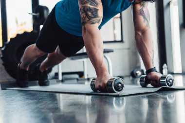 genç sporcu gönderme yapıyor görünümünü kırpılmış ups spor mat spor salonunda dumbbells ile