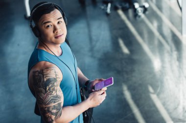 Genç Asyalı sporcu app alışveriş ve müzik ile Smartphone kullanarak 