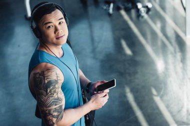 Genç Asyalı sporcu Smartphone kullanarak ve müzik 