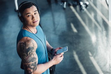 Genç Asyalı sporcu Smartphone kullanarak ve müzik