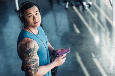 Genç Asyalı sporcu instagram app ile Smartphone kullanarak ve müzik