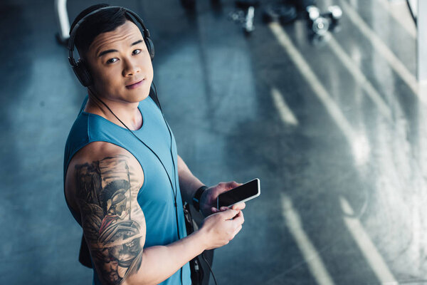 young asian sportsman using smartphone and listening to music 