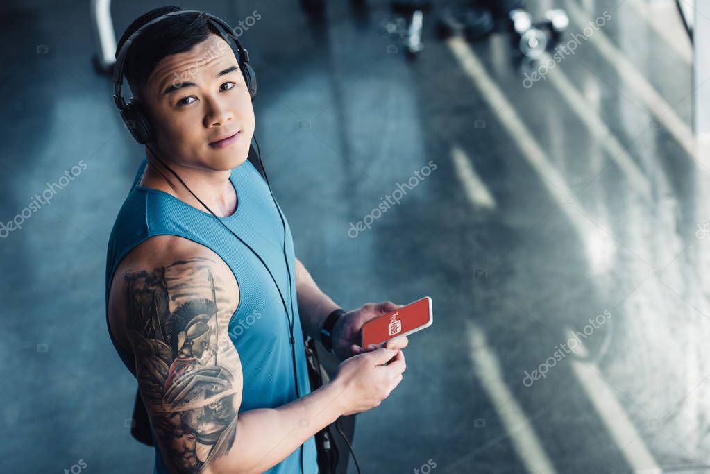 Young asian sportsman using smartphone and listening to music