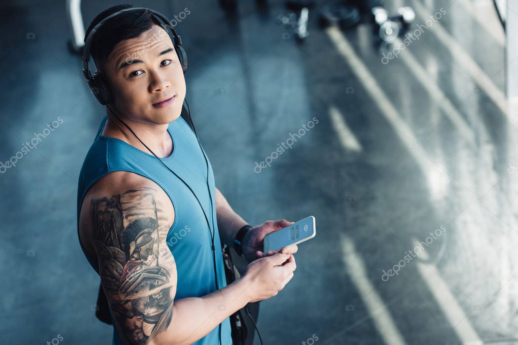 Young asian sportsman using smartphone and listening to music