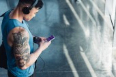 fiatal sportoló használ smartphone, egészségügyi adatok készülék app, és zenét hallgatni 