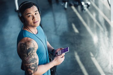 Genç Asyalı sporcu sağlık veri cihazı ile Smartphone kullanarak ve müzik 