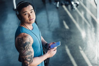 Genç Asyalı sporcu Smartphone kullanarak ve müzik 