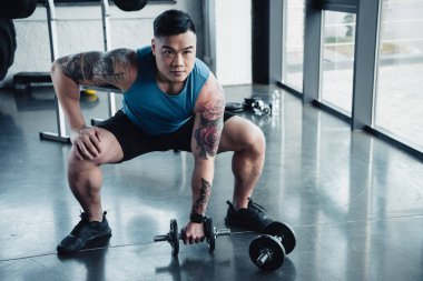 genç sporcu spor salonunda dumbbells ile egzersiz konsantre