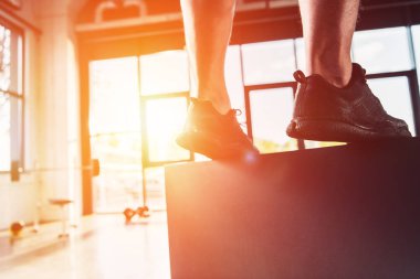 Arka plan üzerinde güneş ışığı ile spor ayakkabı giyen erkek bacak yakın çekim