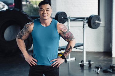 Genç Asyalı sporcu kameraya ile el HIPS spor salonunda seyir 