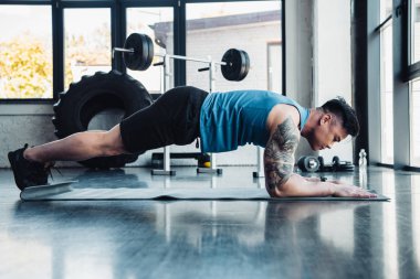genç sporcu spor salonunda tahta egzersiz yaparak yan görünüm