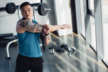 Genç Asyalı sporcu spor salonunda germe egzersiz yaparak