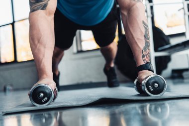kısmi genç sporcu spor mat spor salonunda dumbbells ile egzersiz görünümünü