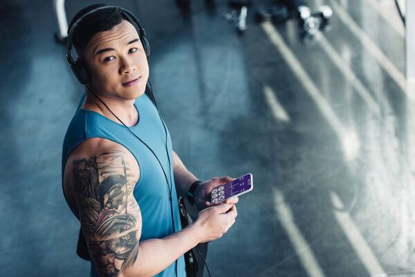 young asian sportsman using smartphone with health data appliance and listening to music 