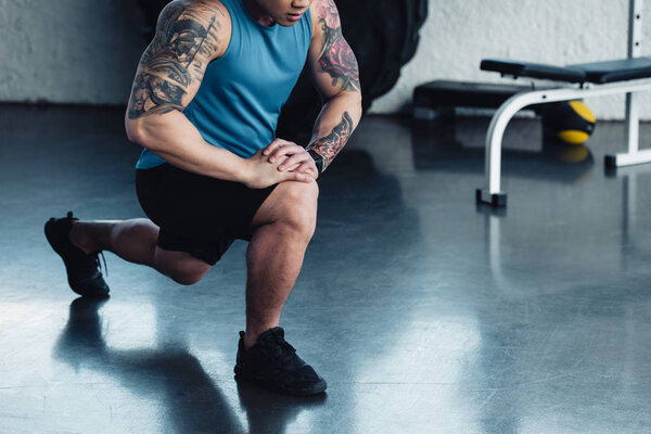 focused young sportsman doing lunge exercise at gym