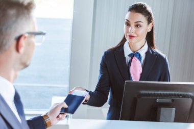 havaalanında check-in sırasında kadın Havaalanı alt belgeleri veren işadamı