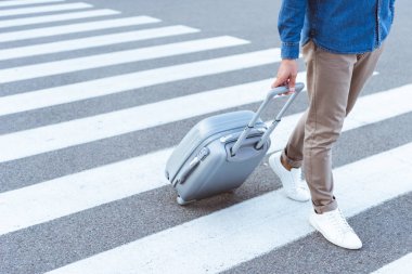 Cropped view of a tourist in white shoes with grey travel bag clipart