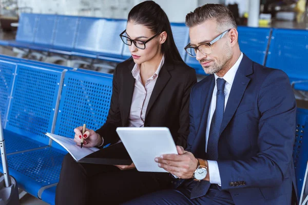 Joven Empresaria Escribiendo Bloc Notas Mientras Hombre Negocios Utilizando Tableta — Foto de Stock