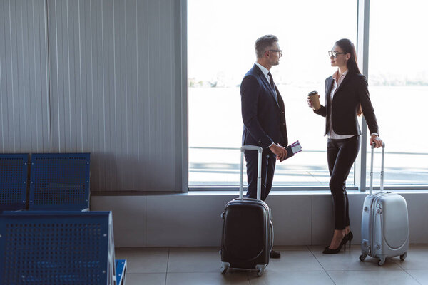 businessman and businesswoman standing and talking at departure lounge in airport
