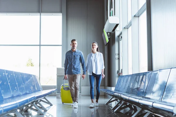 在机场拿着黄色行李走在一起的浪漫情侣 — 图库照片