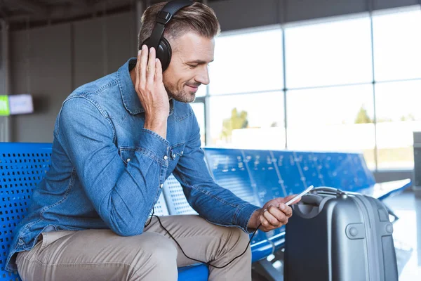 Przystojny Mężczyzna Siedzi Słuchanie Muzyki Lotnisku — Zdjęcie stockowe