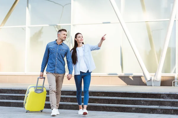 Couple Tourists Holding Hands Smiling Looking Away Pointing Something — Stock Photo, Image