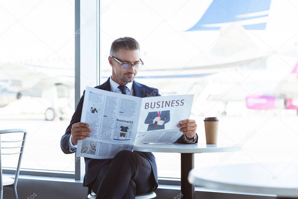 adult businessman reading newspaper in cafe at airport