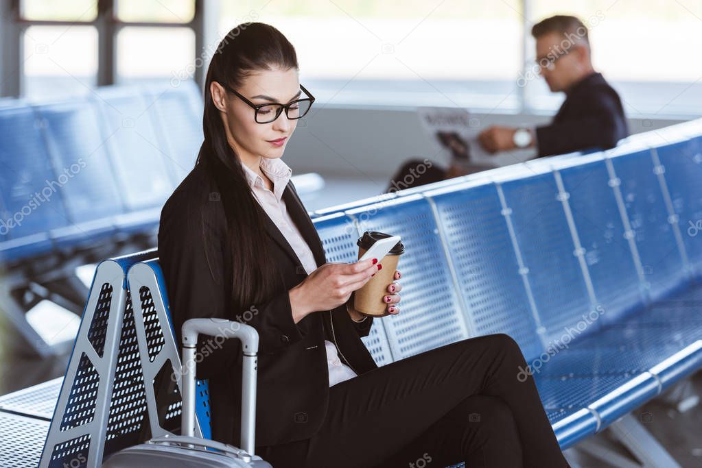 young businesswoman in glasses using smartphone at airport