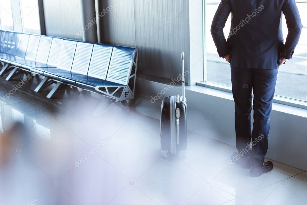 back view of businessman standing at departure lounge in airport