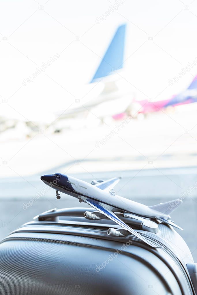 close up of small plane model on grey suitcase in airport