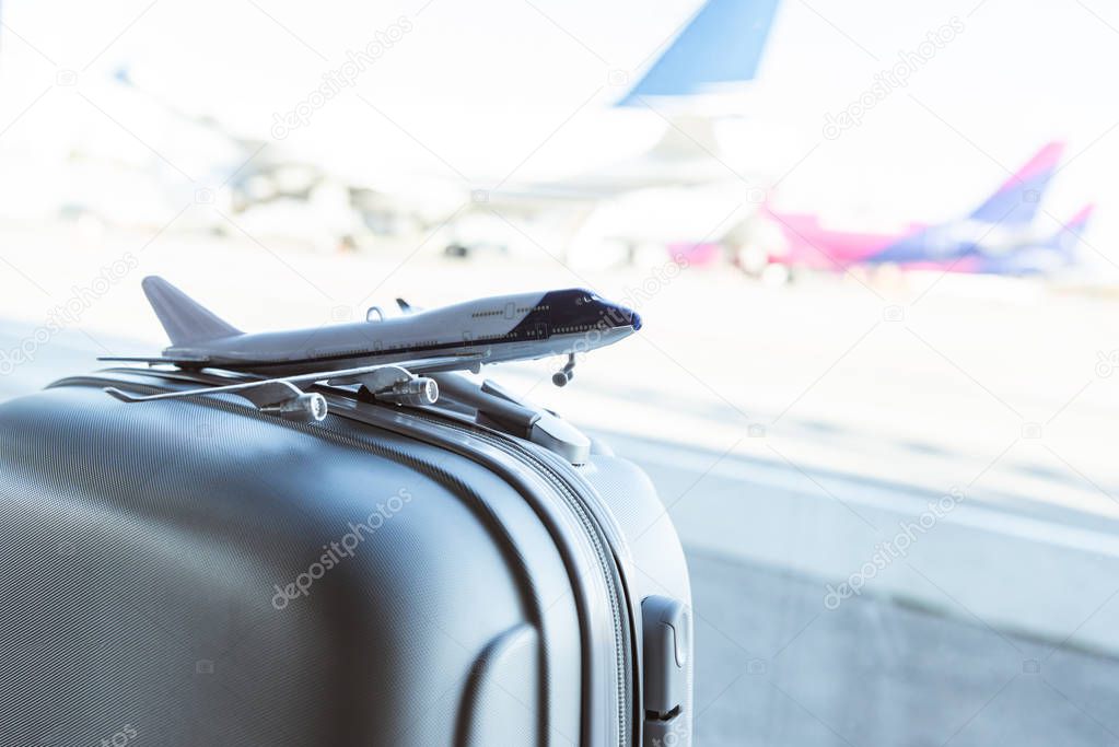 close up of small plane model on grey suitcase in airport