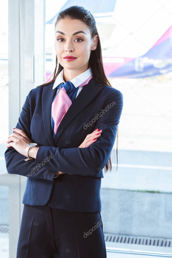 adult female airport worker standing with arms crossed near window 