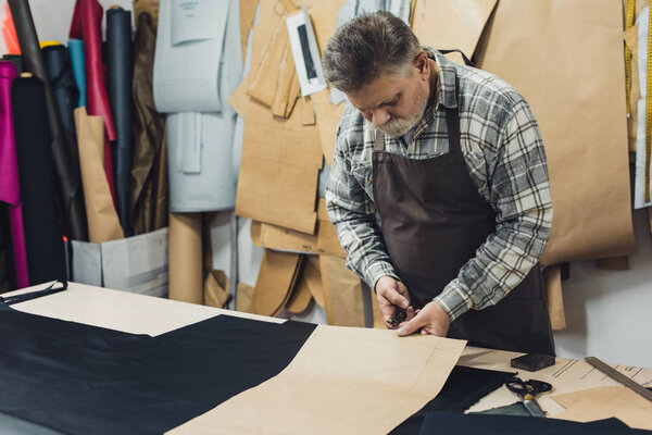 male handbag craftsman in apron working with cardboard at studio