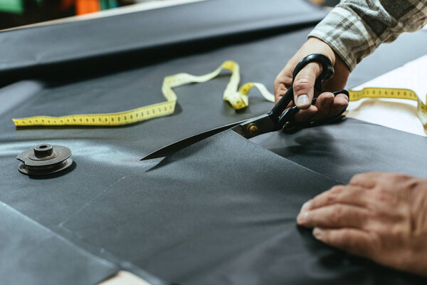обрезанное изображение мужчины ремесленника сумочка резки кожи ножницами в мастерской
