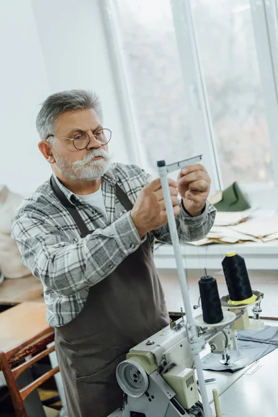 Focused Middle Aged Tailor Apron Cutting Strings Sewing Machine Workshop — Stock Photo, Image