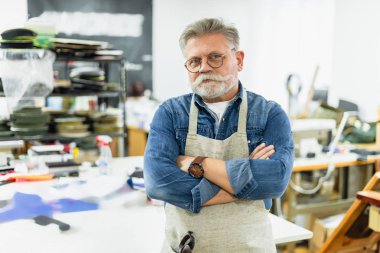 olgun erkek usta Atölyesi'nde çapraz silah ile poz önlük