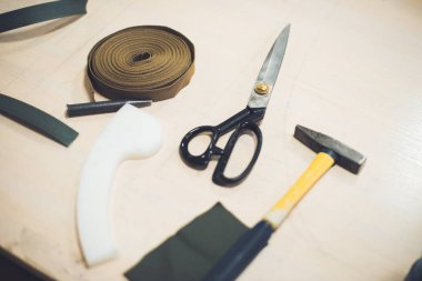 close up view of working table with fabric, hammer and scissors at workshop  clipart