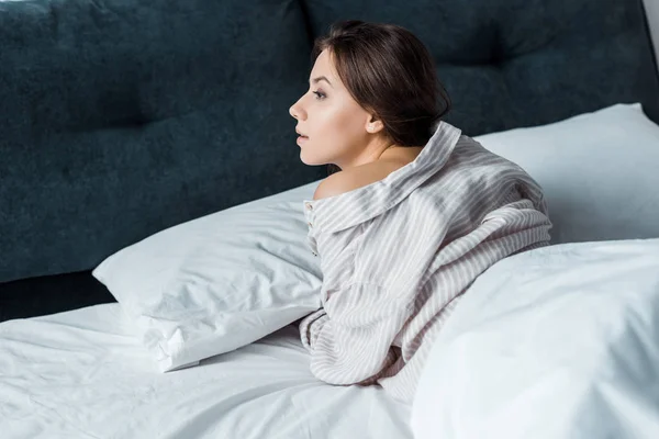 ベッドで横になっているパジャマの魅力的なブルネットの若い女性 — ストック写真