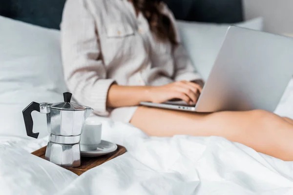 萌香のコーヒー カップとポットとベッドでノート パソコンを持つ女性の選択と集中 — ストック写真