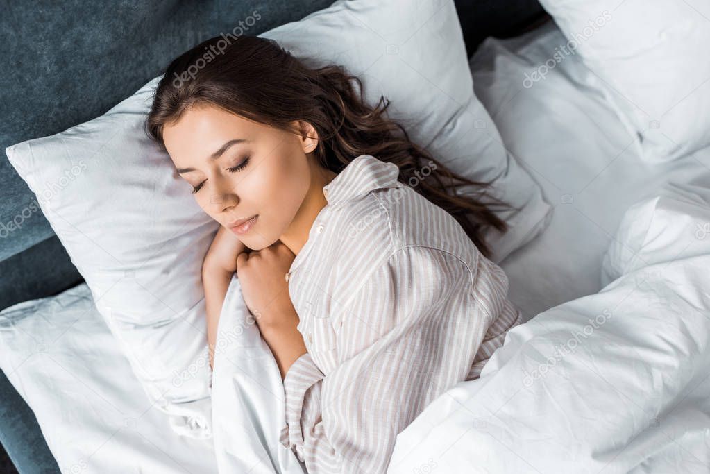 beautiful brunette girl in pajamas sleeping on bed