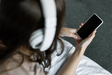 selective focus of girl listening music with smartphone and headphones clipart