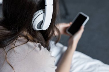kız akıllı telefon ve kulaklık ile müzik dinleme görünümünü kırpılmış