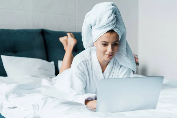 Bela Jovem Mulher Roupão Banho Usando Laptop Enquanto Deitado Cama — Fotografia de Stock