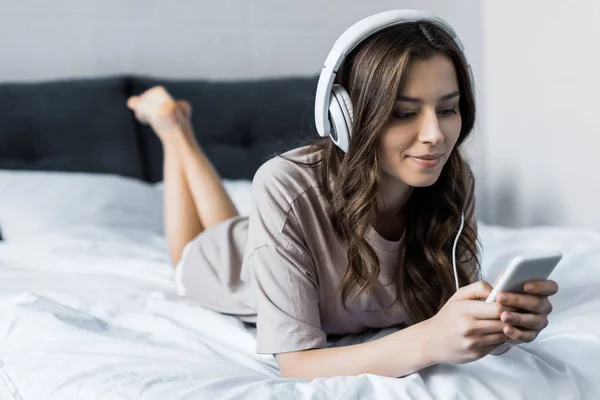 Mooie Brunette Meisje Luisteren Muziek Met Hoofdtelefoons Smartphone Terwijl Liggend — Stockfoto