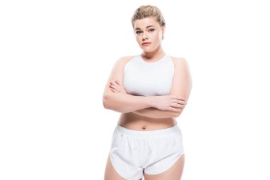 young oversize woman in sportswear standing with crossed arms and looking at camera isolated on white  clipart