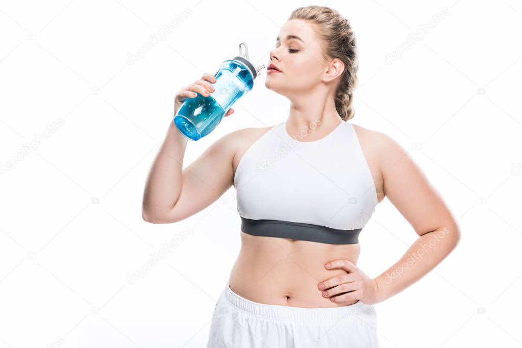 young overweight woman in sportswear drinking water isolated on white
