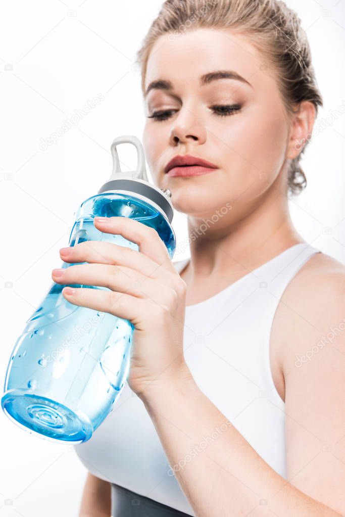 close-up view of young overweight woman drinking water from sports bottle isolated on white 